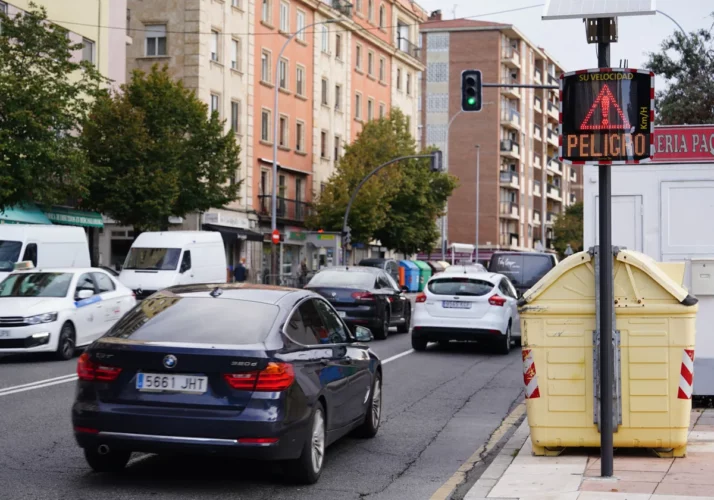 Tráfico intenso en una calle de la ciudad, con un radar pedagógico EVOLIS Vision que muestra un mensaje de 'PELIGRO' y la velocidad de un vehículo en rojo.